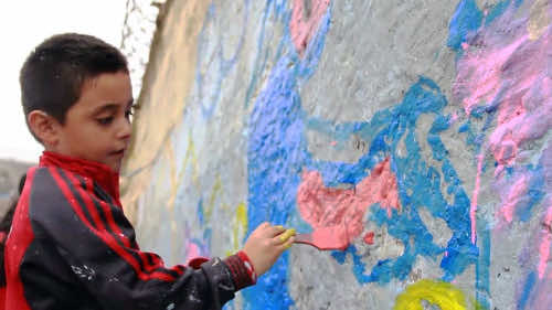 图片显示：墙壁和孩子们与Brigada Muralista组织一起绘画。将有钱人与社会上不幸的人分开的“耻辱之墙”在秘鲁首都利马的郊区上升。当地人说，这是一种耻辱，并将其视频和图像放在互联网上，以羞辱那些建造并支持它的人。电线和水泥的结构高10英尺，也被昵称为“秘鲁的柏林墙”。羞耻的墙将圣胡安德米尔弗雷斯和苏科的社区分开。该线路分割了拉斯·卡萨里纳斯（Las Casuarinas）的城市化，该国一些最富有的居民和隔壁的维斯塔·赫尔莫萨（Vista Hermosa）居住的地方有众多的居民。最初，这堵墙是因为担心可怜的社区的居民会抢劫附近的富裕同胞。从未见过无人机拍摄的墙壁的图像和角度仅加剧富人与穷人之间的辩论。当地的媒体报道说：“数百万磅的房屋在几公里内被蜡烛和破碎的屋顶照亮的木屋形成对比。”YouTube视频显示，赤脚的孩子沿着墙壁的外面行走。 The images also show the indignant slogans graffitied upon it. One sign said: 